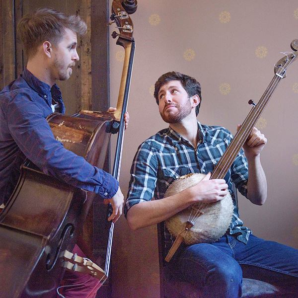 Brad Kolodner, seated with a gourd banjo, looks over his shoulder at bassist Alex Lacquement.