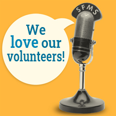 A vintage radio-show microphone with the letters SFMS on it, and a talk balloon that says, We love our volunteers!