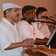 Three Cuban men playing drums and singing