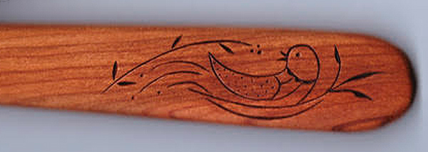 A closeup of a spatula handle decorated with a bird in a nest: a classic Pennsylvania Dutch design.