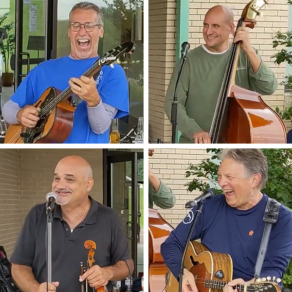 The four members of Sviraj pose as if playing their instruments, grinning and laughing.  They are all middle-aged.  The instruments are fiddle, upright bass, and two guitar-like instruments.