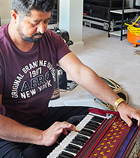 Studnt Bhagirath sits with both hands on the harmonium, concentrating on his playing