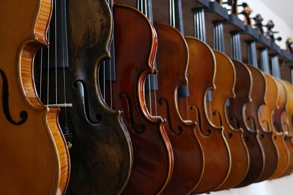 large decorative images of fiddles hanging on a long rack, each somewhat behind the one before it